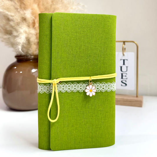 Green notebook with decorative elements on a white surface