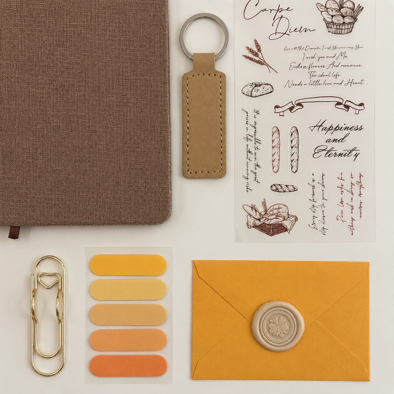Collection of stationery items including a brown notebook, keychain, and envelope on a light background.