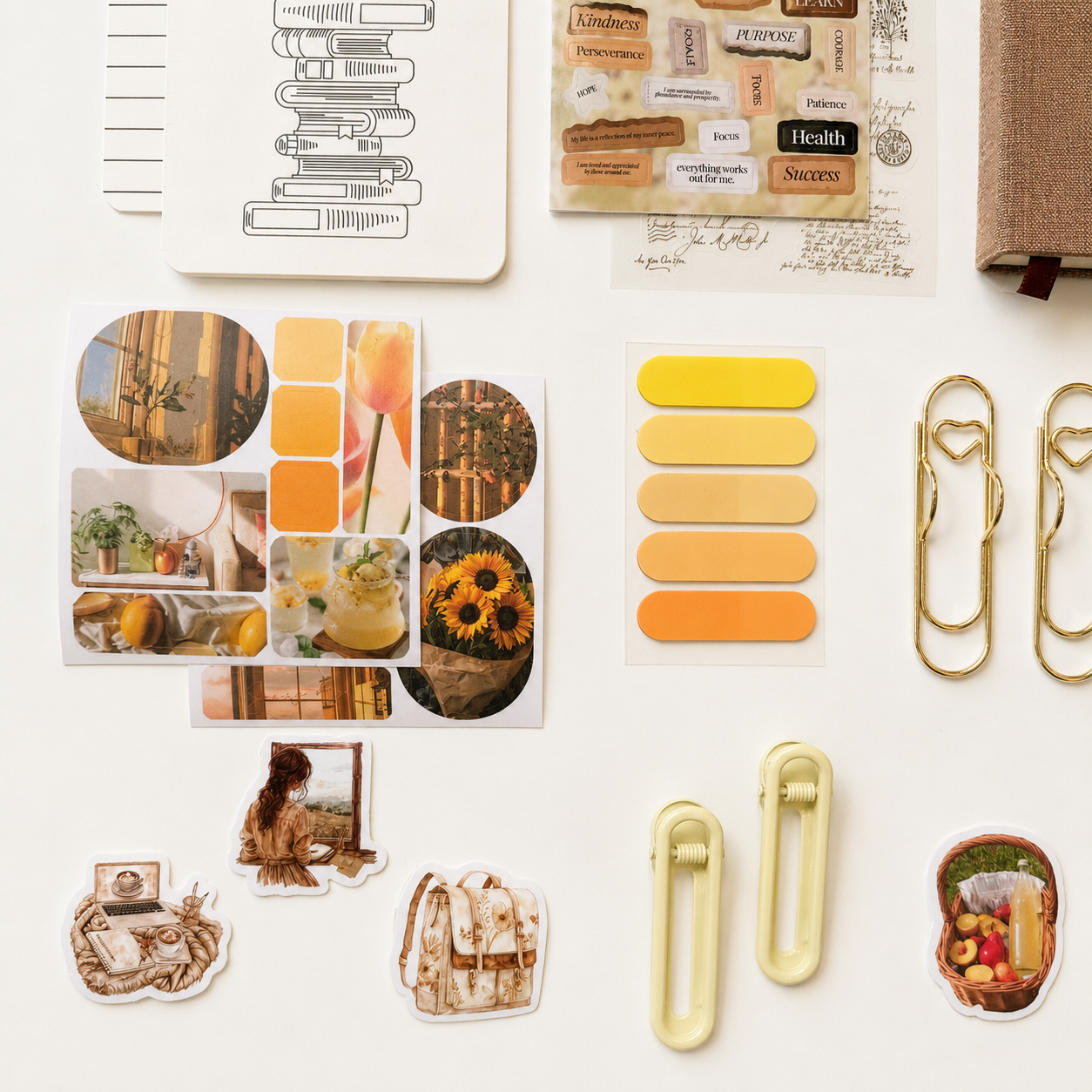 Cozy aesthetic journaling accessories with neutral stickers, pastel page tabs, gold paper clips and warm vintage stationery flat lay