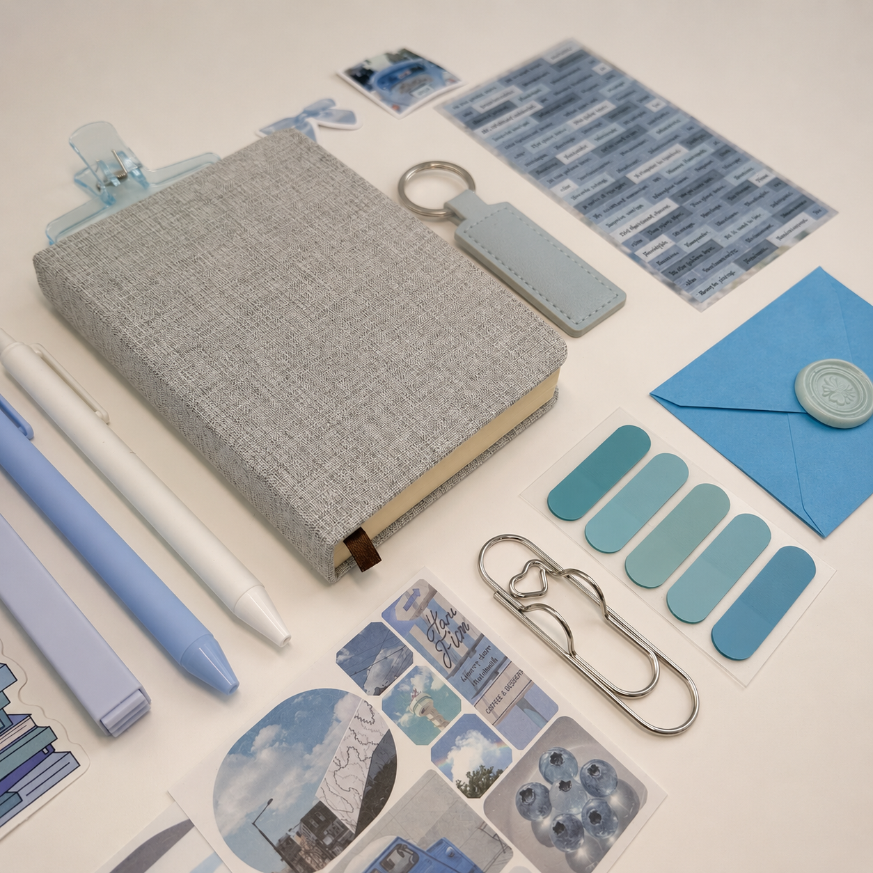 Collection of stationery items including a notebook, pens, and decorative elements on a light background