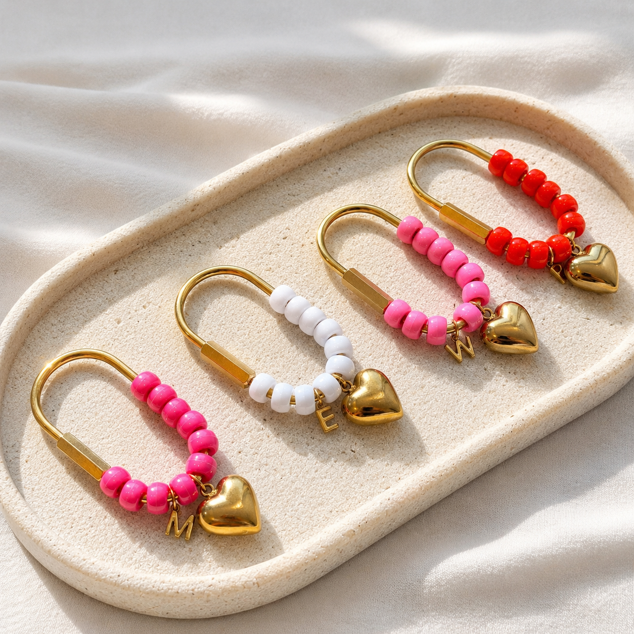 Set of beaded hair ties with heart charms on a beige tray.