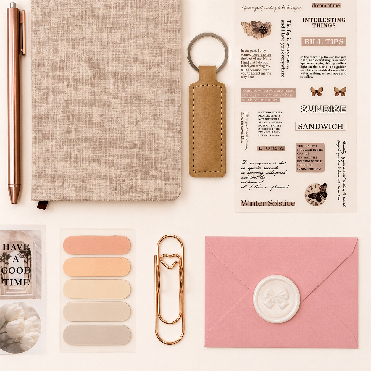Collection of stationery items including a notebook, pen, keychain, and decorative elements on a light background.