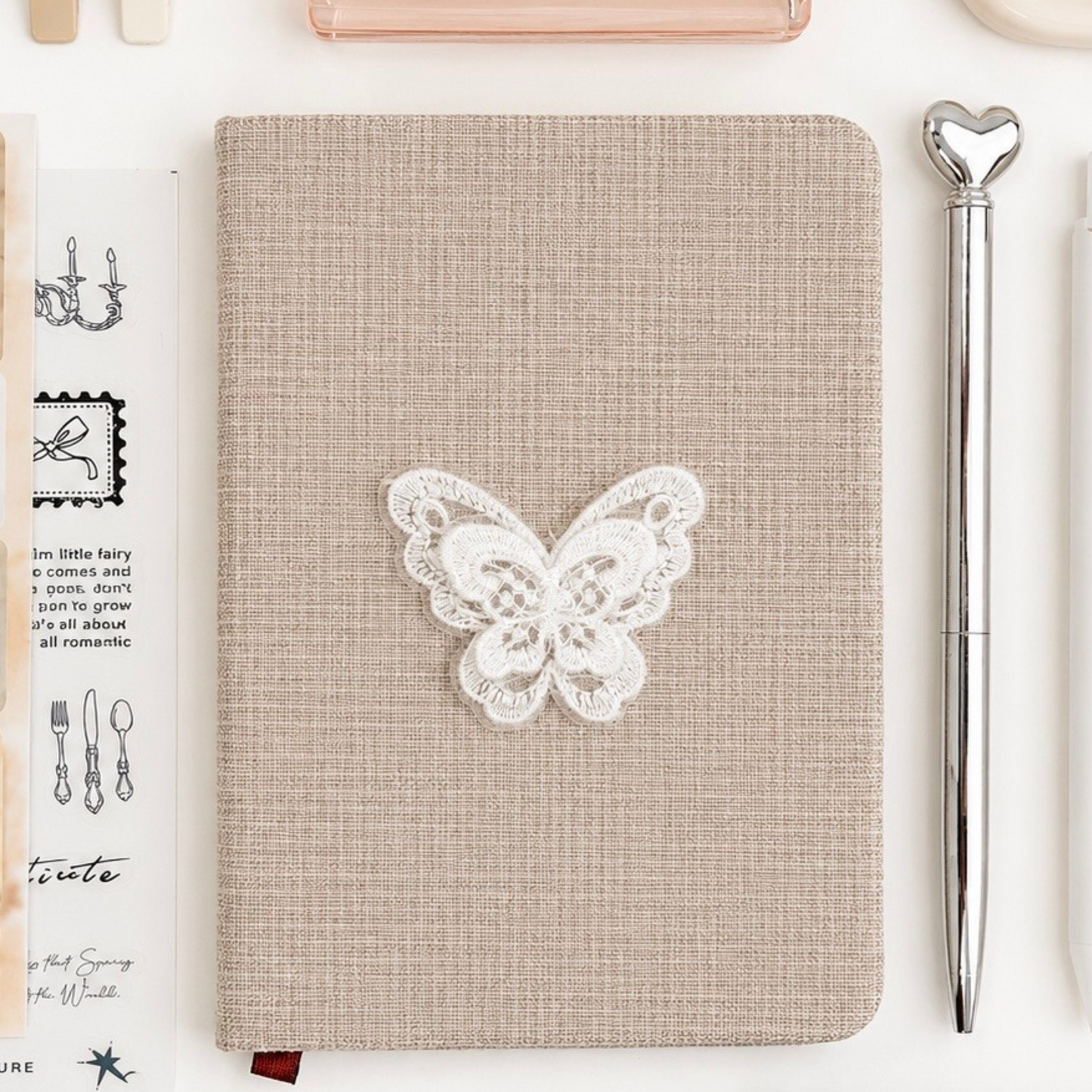 Notebook with butterfly design surrounded by stationery items on a white background