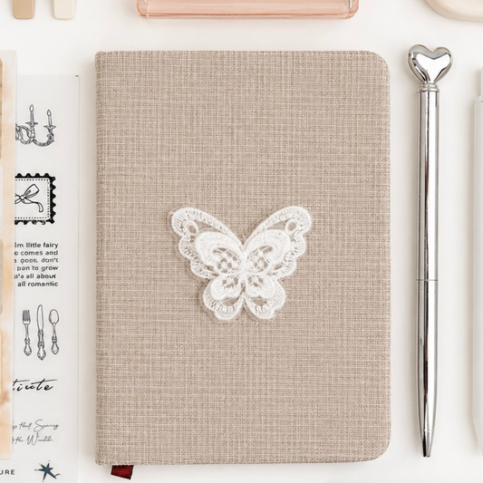 Notebook with butterfly design surrounded by stationery items on a white background