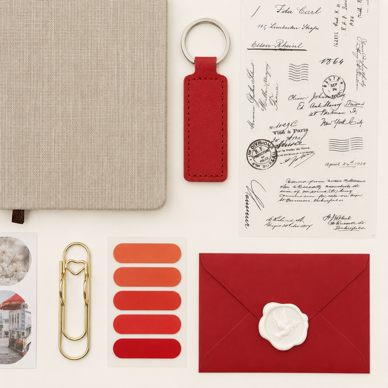 Collection of stationery items including a red keychain, envelope, and paper clips on a textured surface.