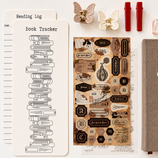 Collection of stationery items including a book tracker, decorative stickers, and a notebook on a white surface.