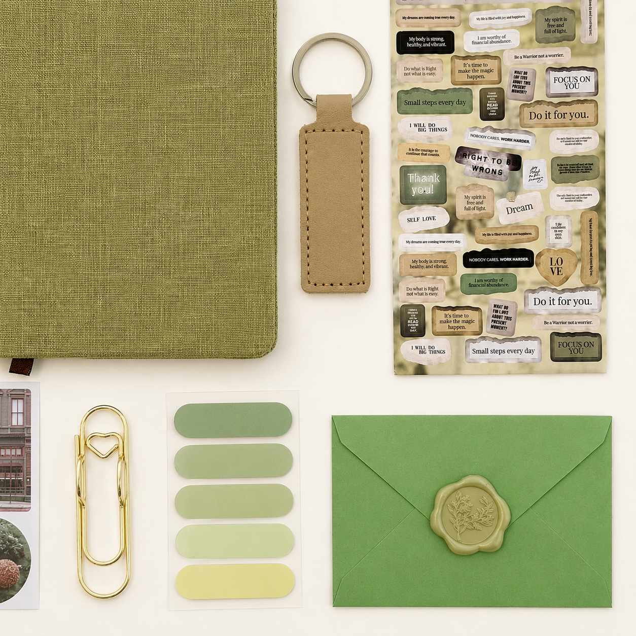 Collection of green stationery items including a notebook, keychain, and envelope on a white background.
