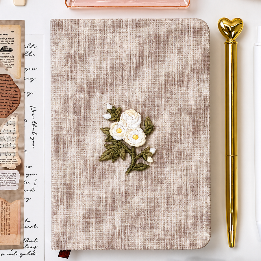 Signature Push Pin Studio linen journal with embroidered white floral detail and elegant gold heart pen