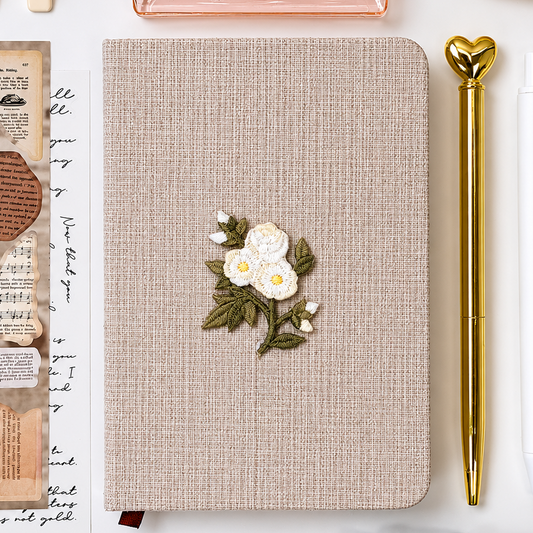 Signature Push Pin Studio linen journal with embroidered white floral detail and elegant gold heart pen