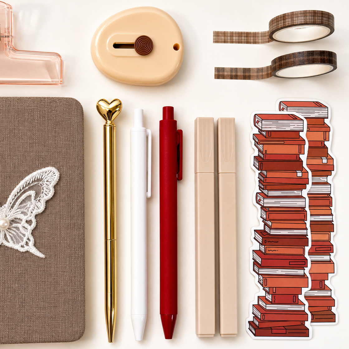 Collection of stationery items including a notebook, pens, and decorative elements on a white background