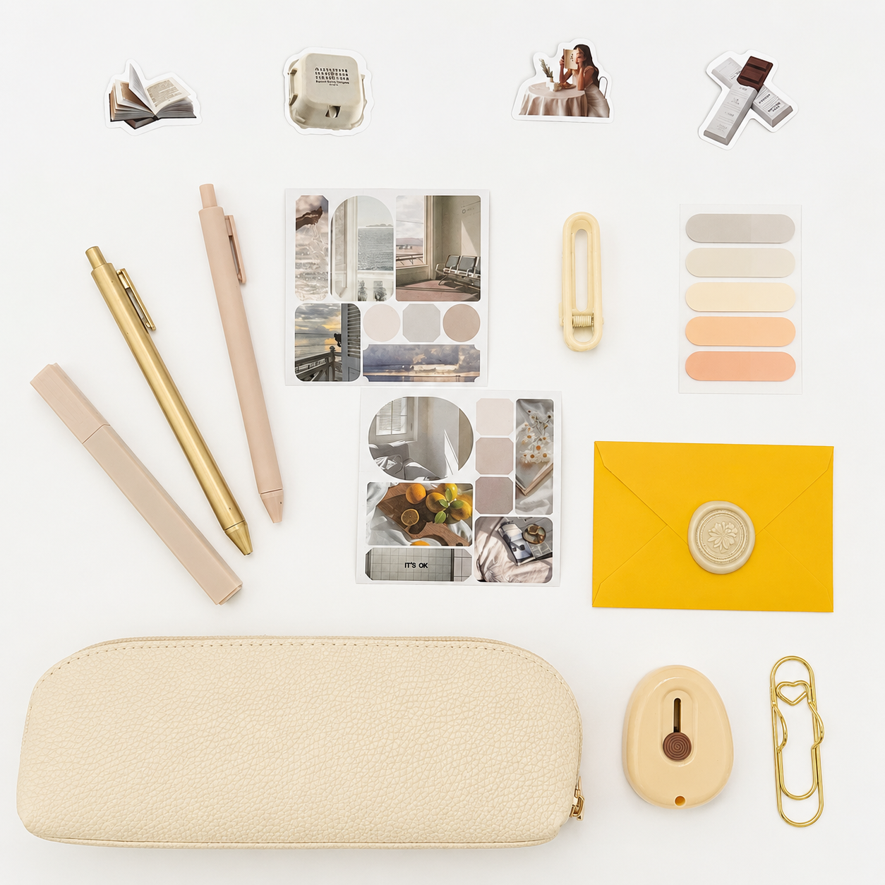 Collection of stationery items including pens, a wallet, and decorative elements on a white background