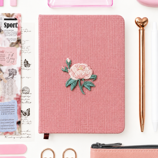 Pink notebook with floral design on a white background