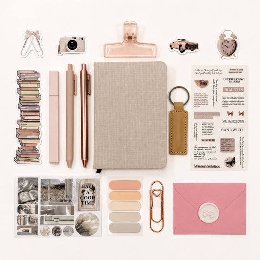 Collection of stationery items including a notebook, pens, clips, and other small objects on a white background.