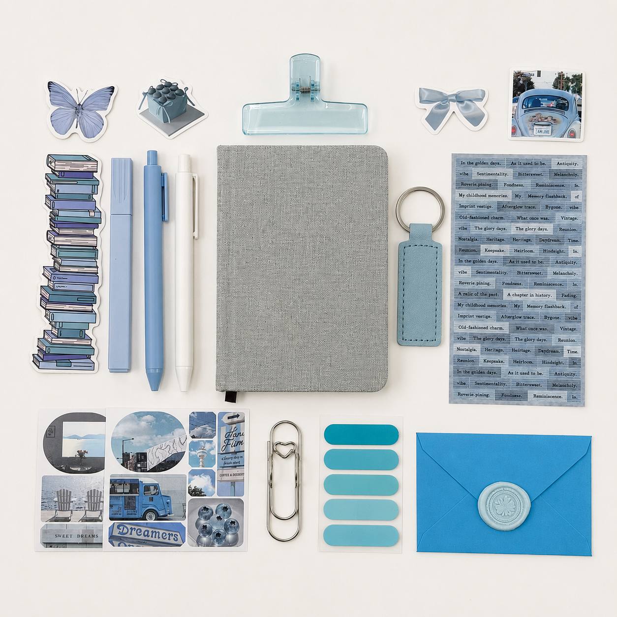 Collection of stationery items including a notebook, pens, clips, and decorative elements on a white background.