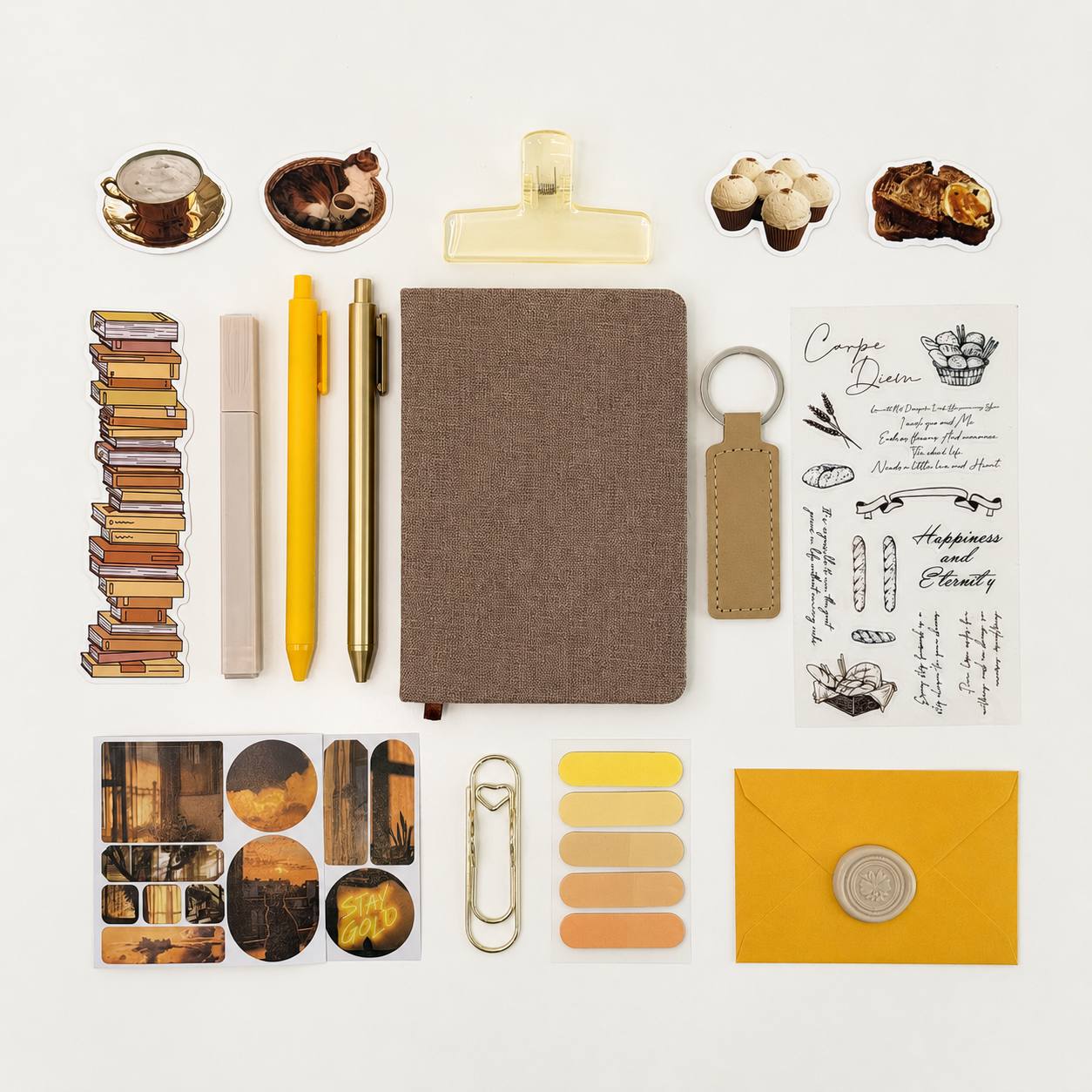 Collection of stationery items including a notebook, pens, clips, and decorative elements on a light background.