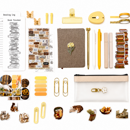 Collection of stationery items including a notebook, pen, clips, and decorative elements on a white background.